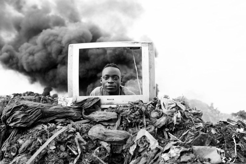 A young boy is playing behind a discarded TV frame at the Hulene dump in Maputo. Many electronic items are sent to the dump every day, and the people who live and work on the site recycle them for reuse and resale on the black market. They also have to navigate the huge number of items which will not see reuse. There is limited regulatory oversight on e-waste processing in Mozambique, and e-waste is causing serious health and pollution problems in the area.